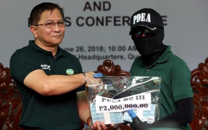 <p><strong>REWARD FOR AGENTS.</strong> Philippine Drug Enforcement Agency (PDEA) Director General Aaron Aquino hands over the PHP2 million cash reward to an agent from PDEA Regional Office III as part of the Operation: "Lawmen", an incentive program for law enforcers and members of anti-illegal drug units/teams or task forces, at the PDEA compound in Quezon City on Tuesday (June 26, 2018). The PDEA RO III succesfully confiscated 71, 205.10 grams of shabu worth PHP356.03 million in BF Martinville Subdivision, Barangay Manuyo in Las Piñas City on June 13, 2017<em>. (PNA photo by Joey O. Razon)</em></p>